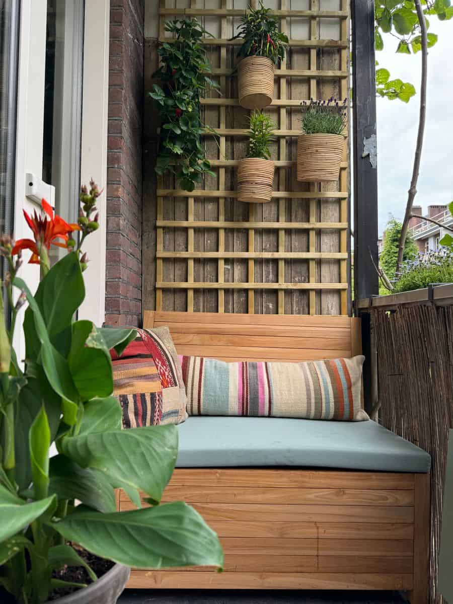Klein balkon inrichten: 8 slimme en stijlvolle ideeën Klein balkon ingericht met een ruimtebesparende balkonbank met opbergruimte met daarboven een trellis voor het creëeren van een verticale balkontuin.